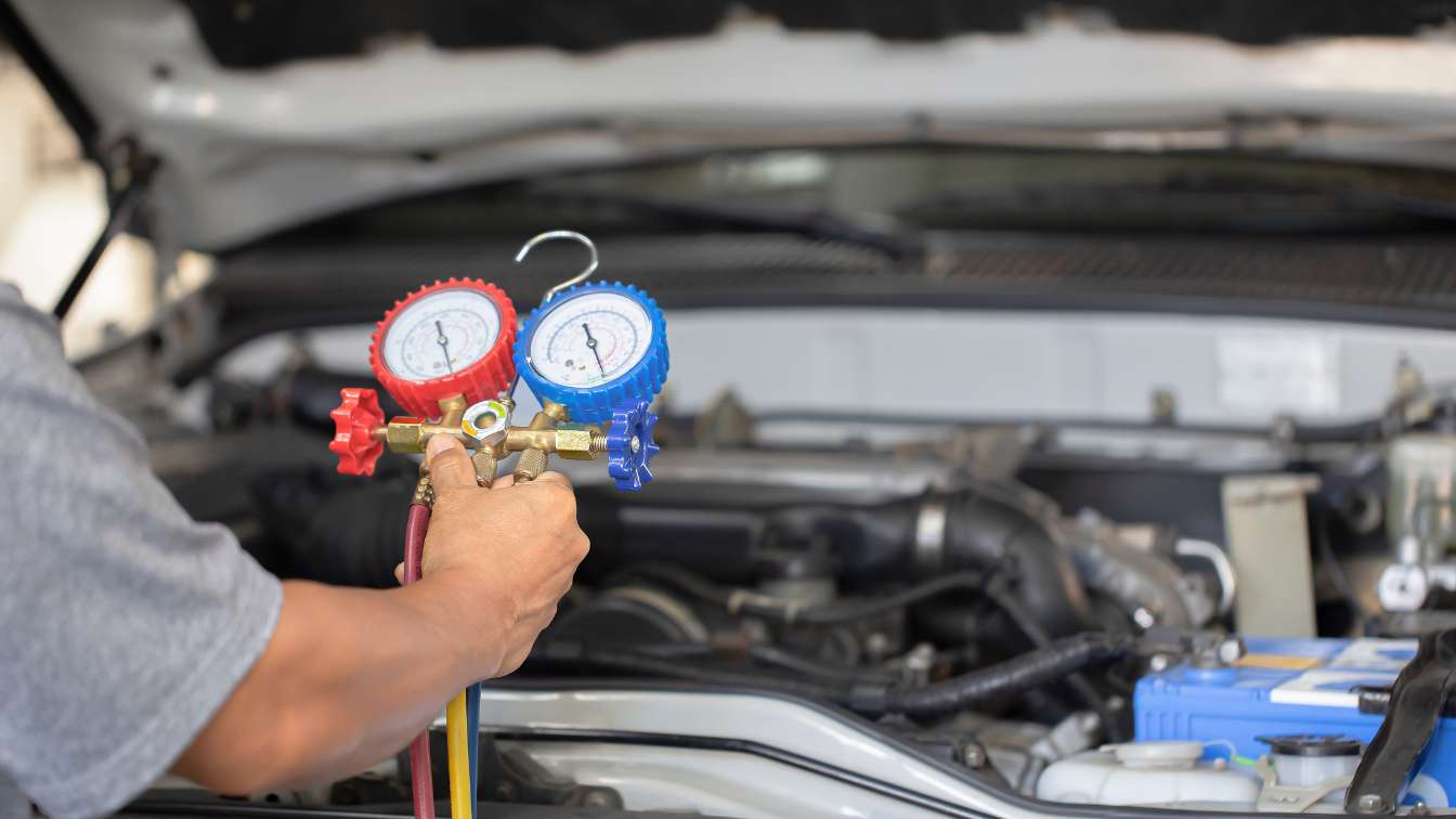 Technician checking a vehicle air-conditioning system with manifold gauges