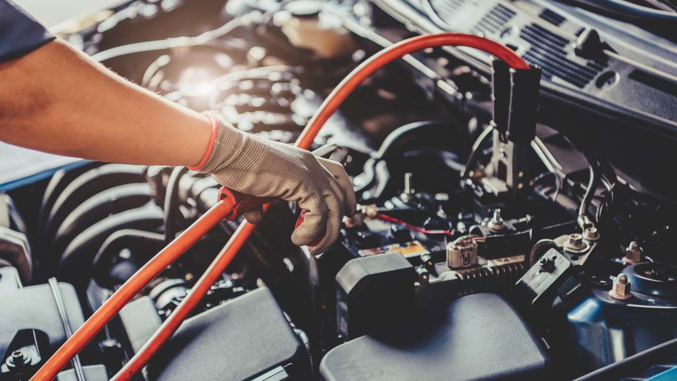 Technician connecting test leads to a vehicle battery during electrical testing