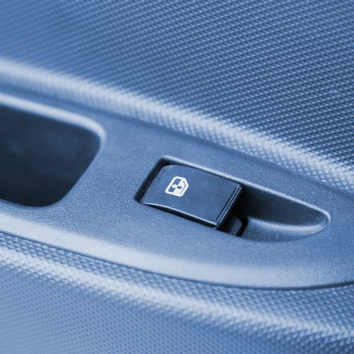 Close-up of a car's power window switch on a textured surface.