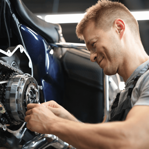 A man works on a motorcycle engine, focusing on adjusting its components.